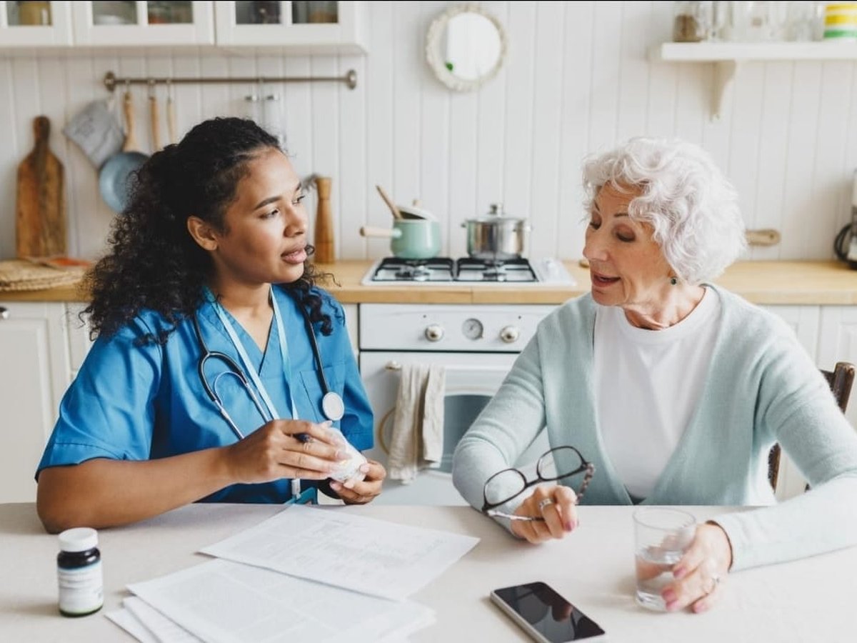 A care professional reviewing medications with an older patient at home